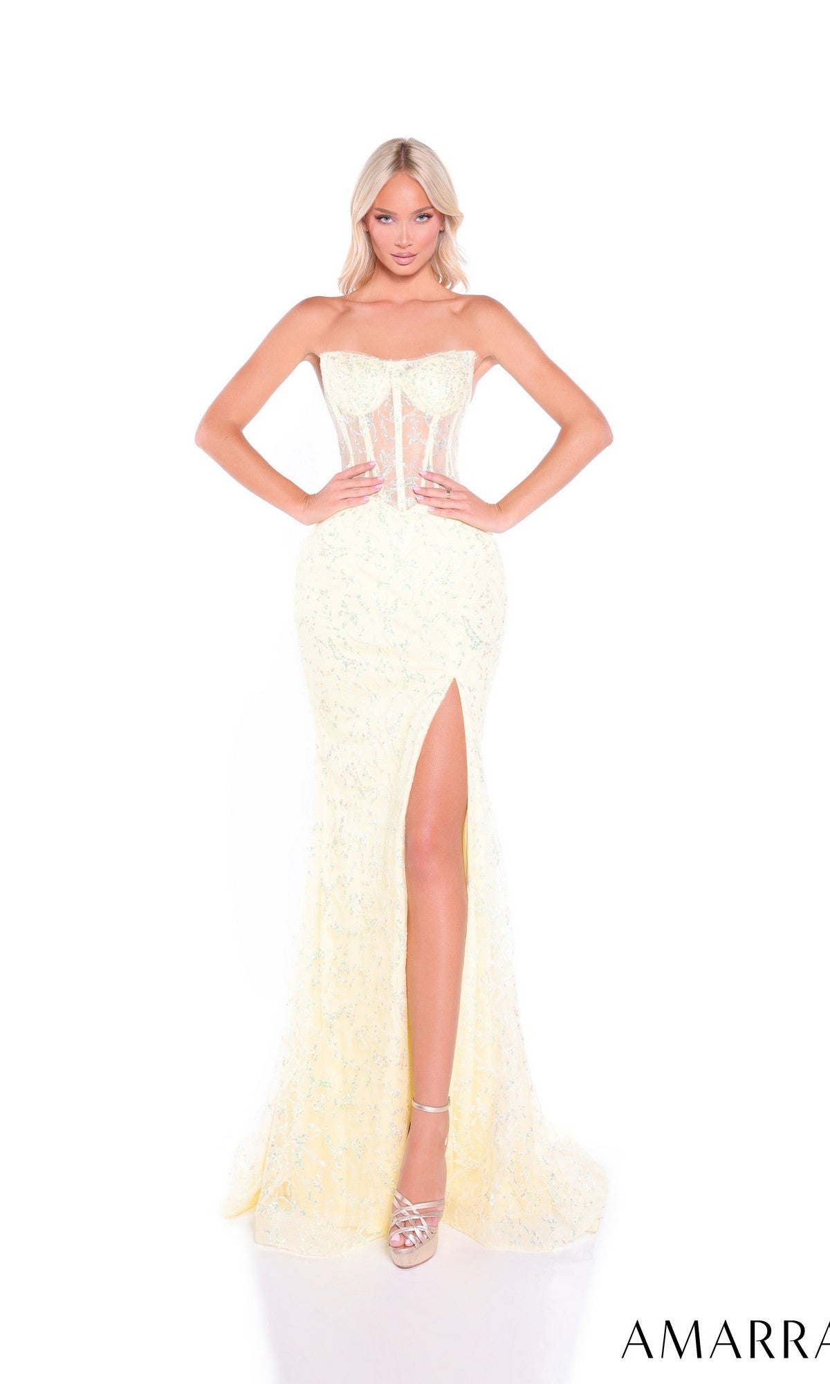 A woman poses against a white background in the Amarra 89490 long prom dress, featuring a strapless corset bodice, sparkling embroidery, sequin details, a thigh-high slit, and high-heeled sandals.